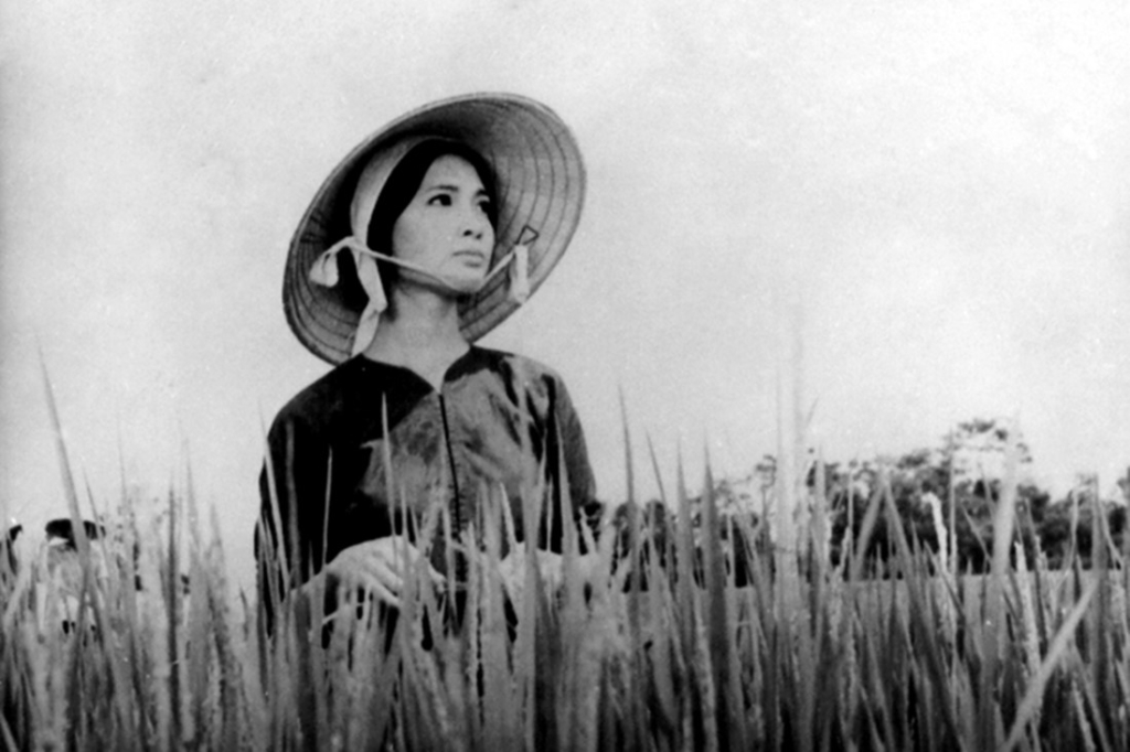 Black and white still of a woman wearing a traditional hat.